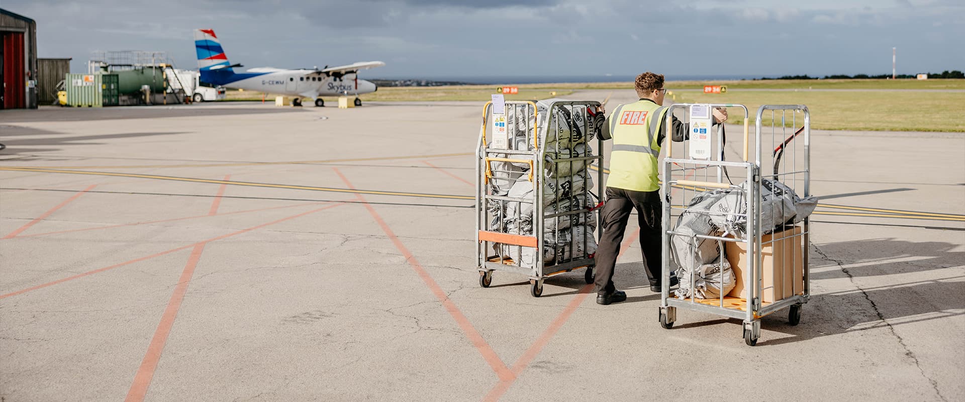 employee handling airfreight for Skybus, Land's End Airport airfield