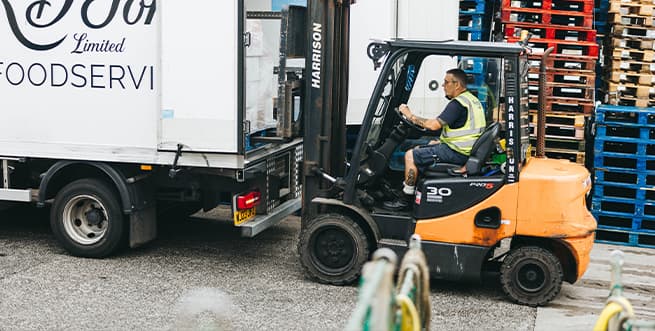 Person driving forklift truck to unload a lorry full of freight on Penzance quay