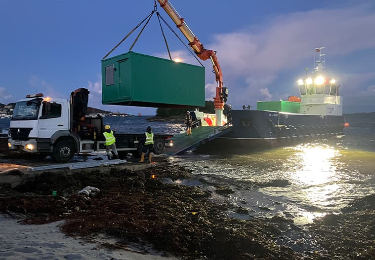 Gugh unloading green modular cabins with crane onto a flat bed lorry on St Mary's - Isles of Scilly Freight