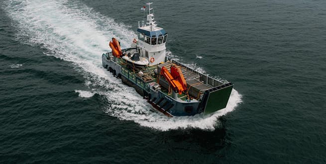 drone image of the landing craft Gugh sailing loaded with cargo