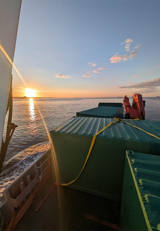 Gugh sailing at sun rise transporting green modular cabins