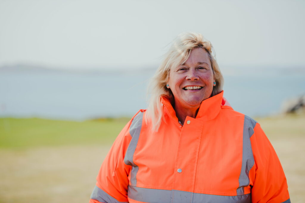 Jeanette Ware, Island Operations Manager, smiling at the camera in a high visibility jacket