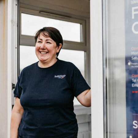 Employee standing in front of the entrance of the Isles of Scilly Freight office in Penzance