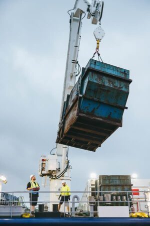 Waste container being loaded by Menawethan's crew onto the ship