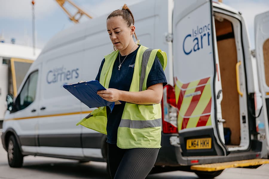 Woman standing in front of a delivery van with a clipboard